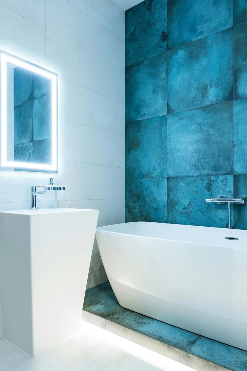 White freestanding tub with teal accent tile wall and LED mirror