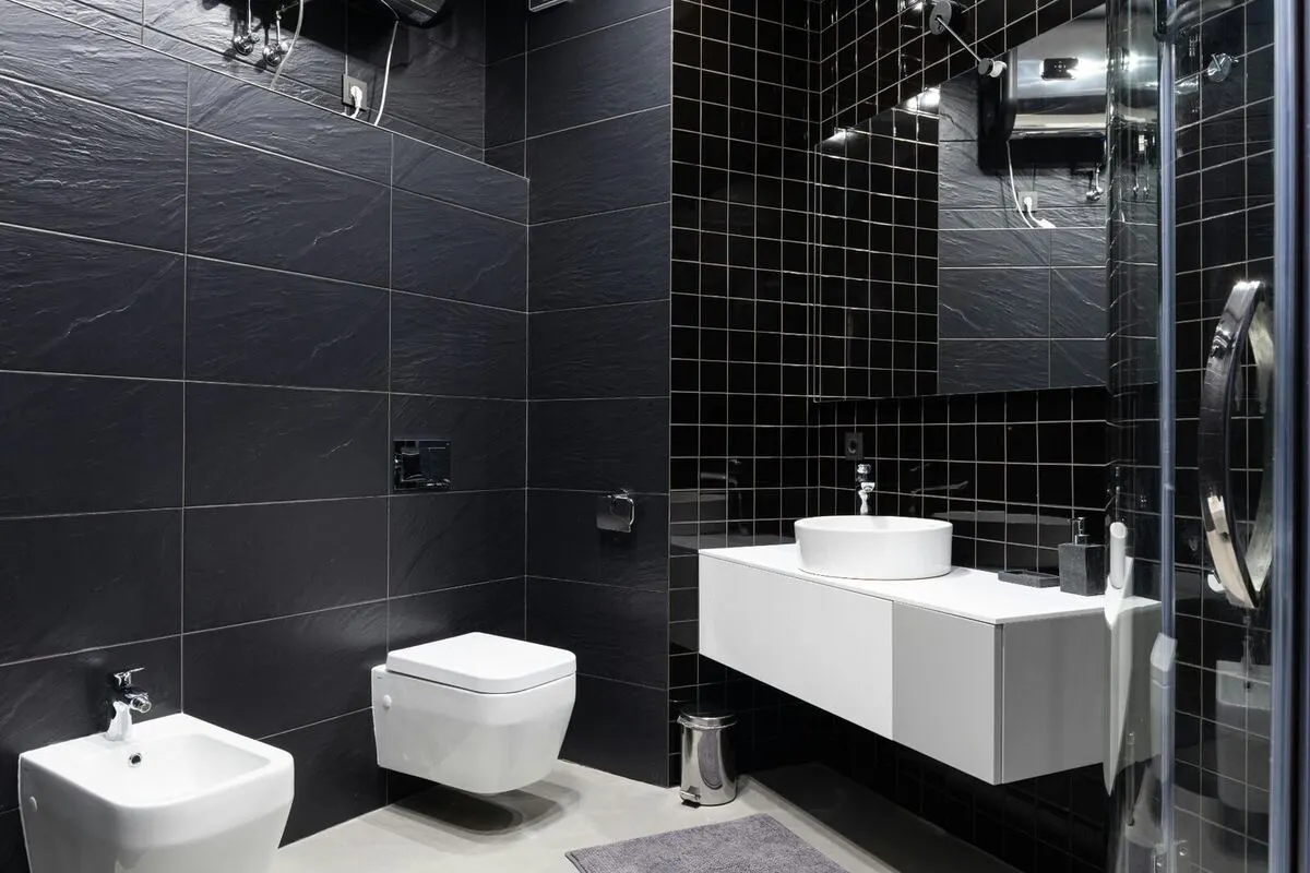 Matte black slate tile bathroom with floating white vanity and glass shower