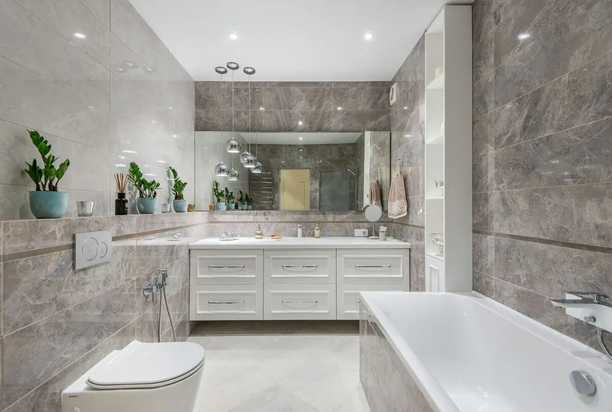 Gray marble bathroom with white vanity chrome pendants and soaking tub