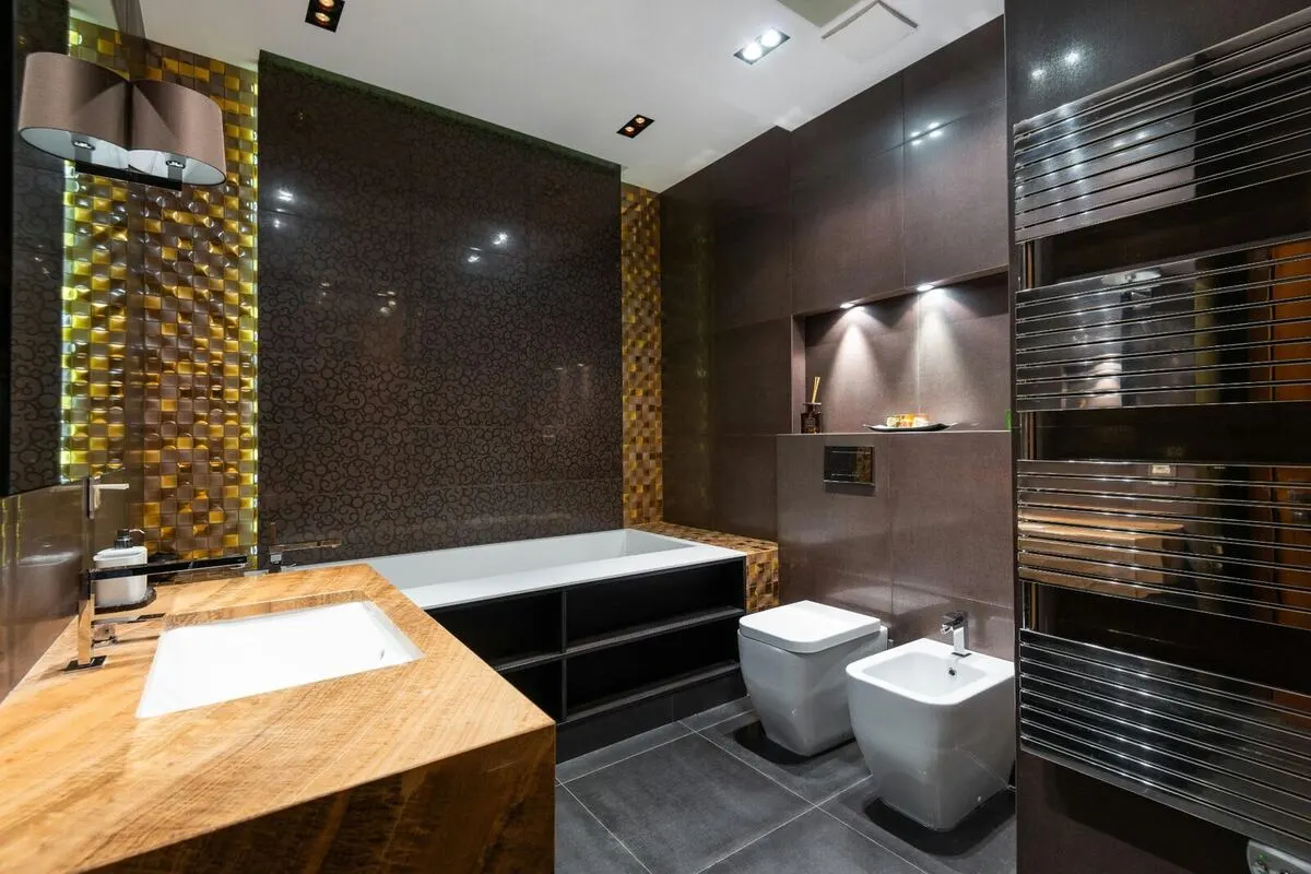 Dark luxury bathroom with gold mosaic accent wood vanity and soaking tub