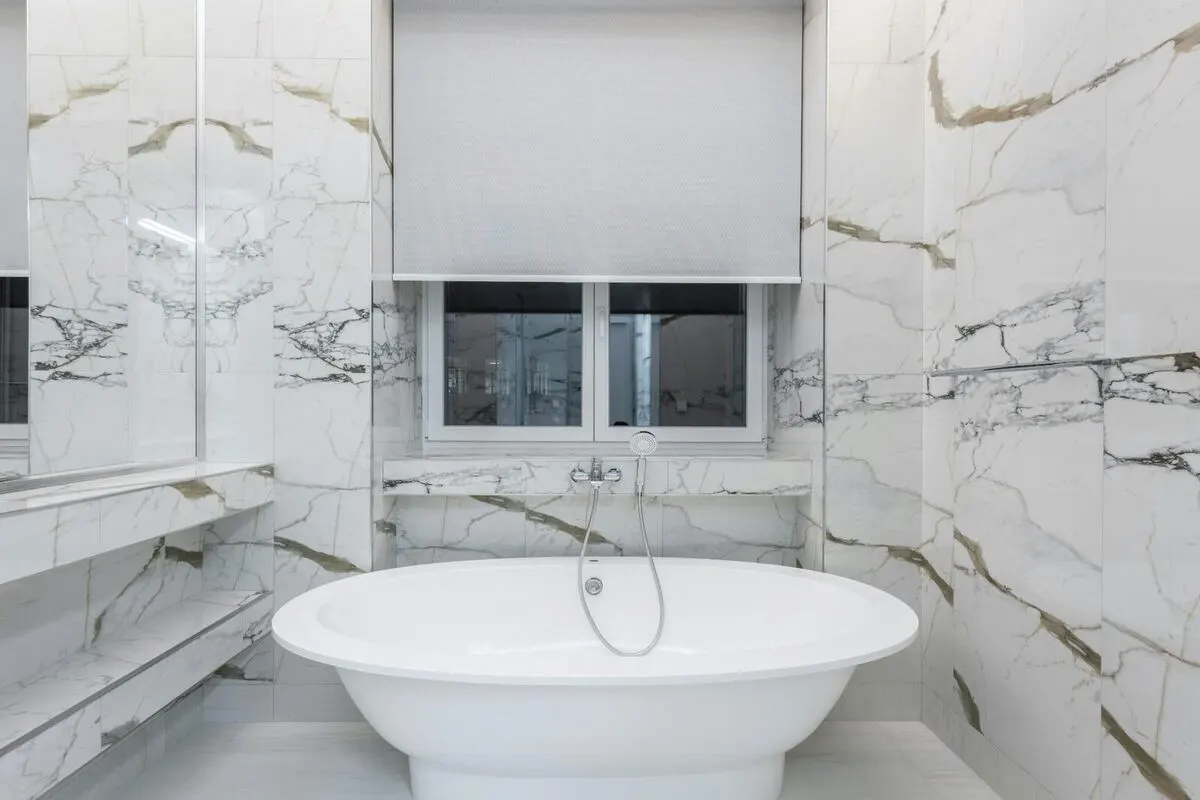 Calacatta slab bathroom with freestanding bowl tub and marble bench