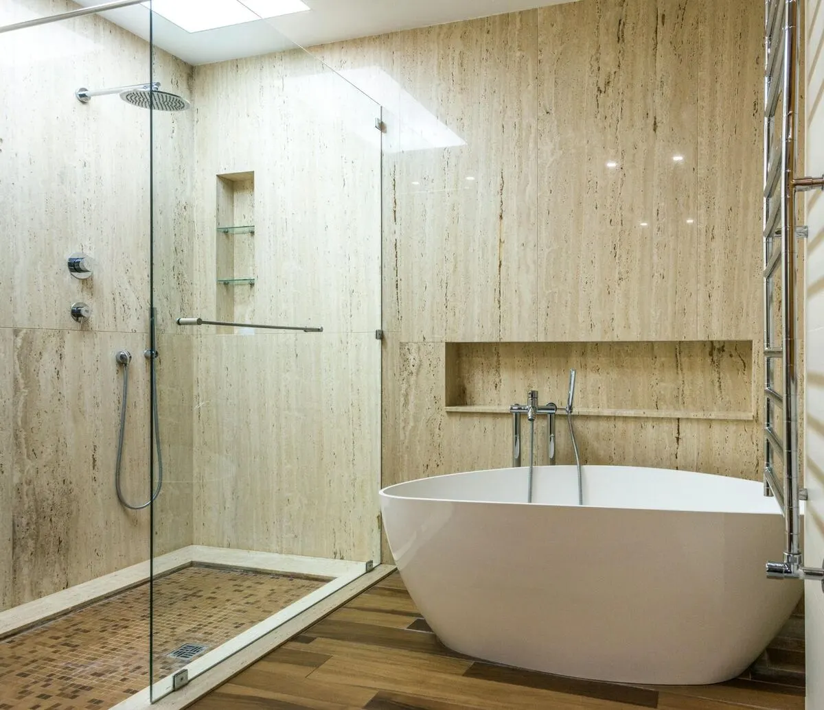 Travertine wet room with frameless glass shower freestanding tub and niche shelving
