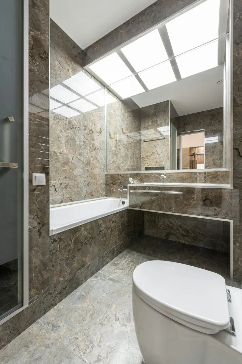 Brown emperador marble bathroom with skylight tub and wall mounted sink