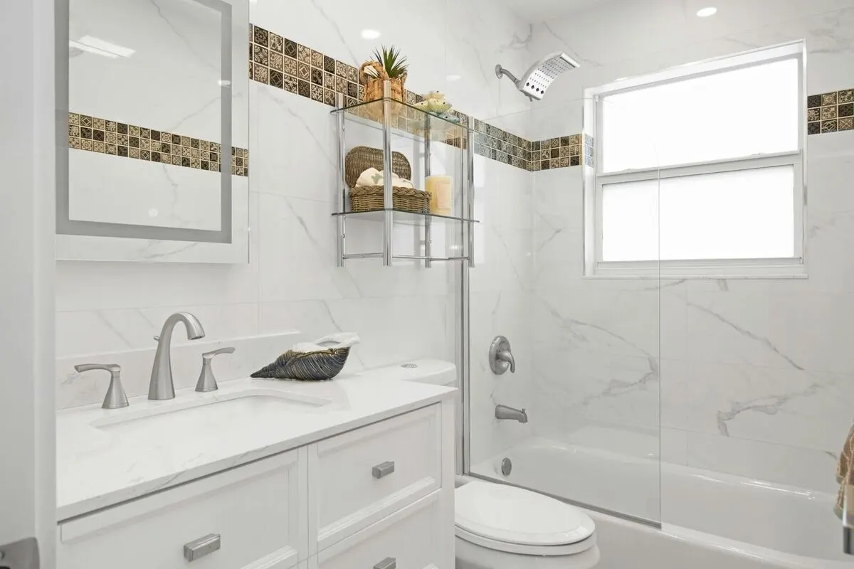 White marble bathroom with decorative tile border glass shower partition